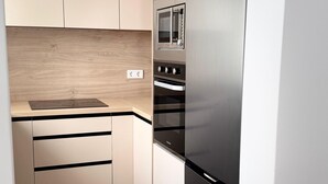A compact kitchen with a built-in oven, a microwave, and a stainless steel refrigerator. - Beautiful Beach House with a 40 m² Sunny Terrace and a 5-Minute Walk to the Beach (Torrevieja)