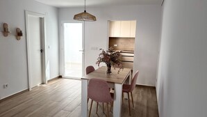 A modern kitchen with wooden cabinets, a dining table with chairs, and a hanging light fixture. - Beautiful Beach House with a 40 m² Sunny Terrace and a 5-Minute Walk to the Beach (Torrevieja)