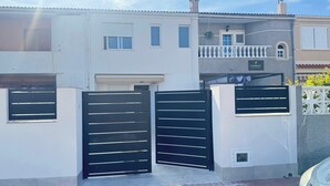 A two-story building with a gated entrance, a balcony, and a sign indicating a business or office space. - Beautiful Beach House with a 40 m² Sunny Terrace and a 5-Minute Walk to the Beach (Torrevieja)