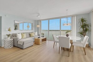 Ein modernes Wohnzimmer mit einer Couch, einem Esstisch, Stühlen und einem großen Fenster mit Blick.
