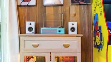 A wooden wall with framed pictures, a speaker setup, and a Monopoly game box.