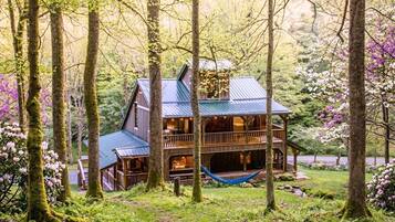 A wooden cabin surrounded by trees and a hammock.