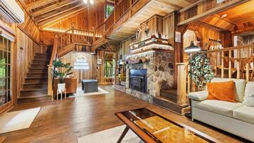 Un intérieur spacieux en bois, agrémenté d’une cheminée en pierre, d’un escalier et d’un coin salon confortable.