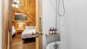 A wooden room with a bed, nightstand, and a painting on the wall.