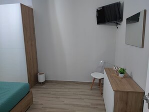 A room with a bed, a desk, a chair, a TV, and a small trash bin. - Seamus House, Briatico (Briatico)
