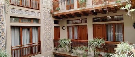 A multi-level courtyard with balconies, potted plants, and traditional architectural details.