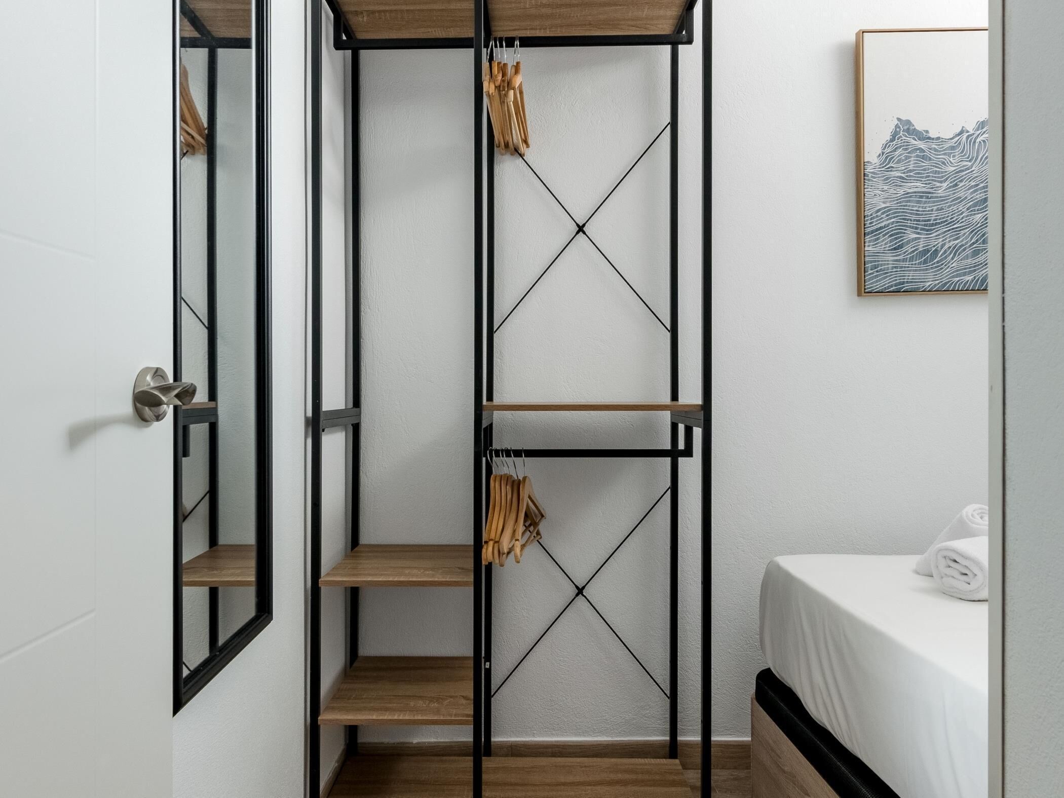 Een slaapkamer met een bed, een houten plankunit en een kunstwerk in een lijst aan de muur.