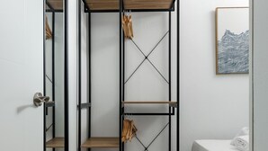 Een slaapkamer met een bed, een houten plankunit en een kunstwerk in een lijst aan de muur.