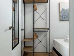 A bedroom with a bed, a wooden shelf unit, and a framed artwork on the wall. - Río Manzanares I - One-Bedroom Apartment (Ciudad de Madrid)