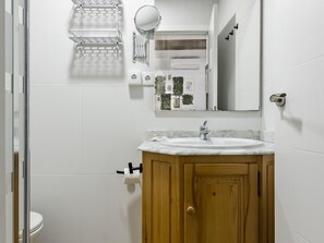 A bathroom with a wooden vanity, a white sink, a mirror, and a towel rack. - Río Manzanares I - One-Bedroom Apartment (Ciudad de Madrid)
