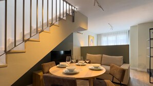 A modern living room with a dining area, a staircase, and a sofa. - Málaga Apartments by Charming VII - Studio with terrace (Málaga)