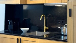 A modern kitchen with wooden cabinets, a black countertop, a gold faucet, and a kettle. - Málaga Apartments by Charming VII - Studio with terrace (Málaga)