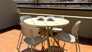 Een terras met een ronde tafel en vier stoelen, een schaal en een kopje op tafel.
