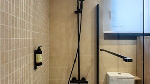 Douchegedeelte met een handdouche, een shampoo en een toilet.