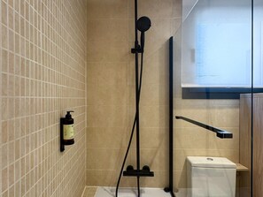 A shower area with a handheld showerhead, a bottle of shampoo, and a toilet. - Málaga Apartments by Charming VIII - Studio with terrace (Málaga)