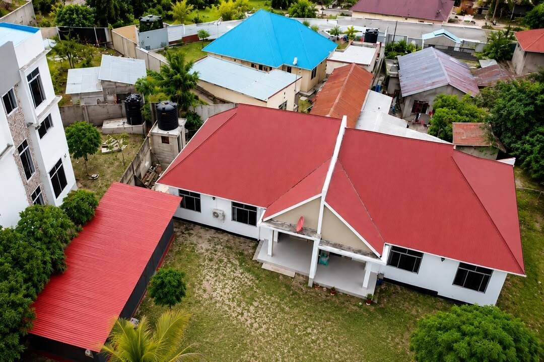 A residential building with a red roof, white walls, and a balcony.