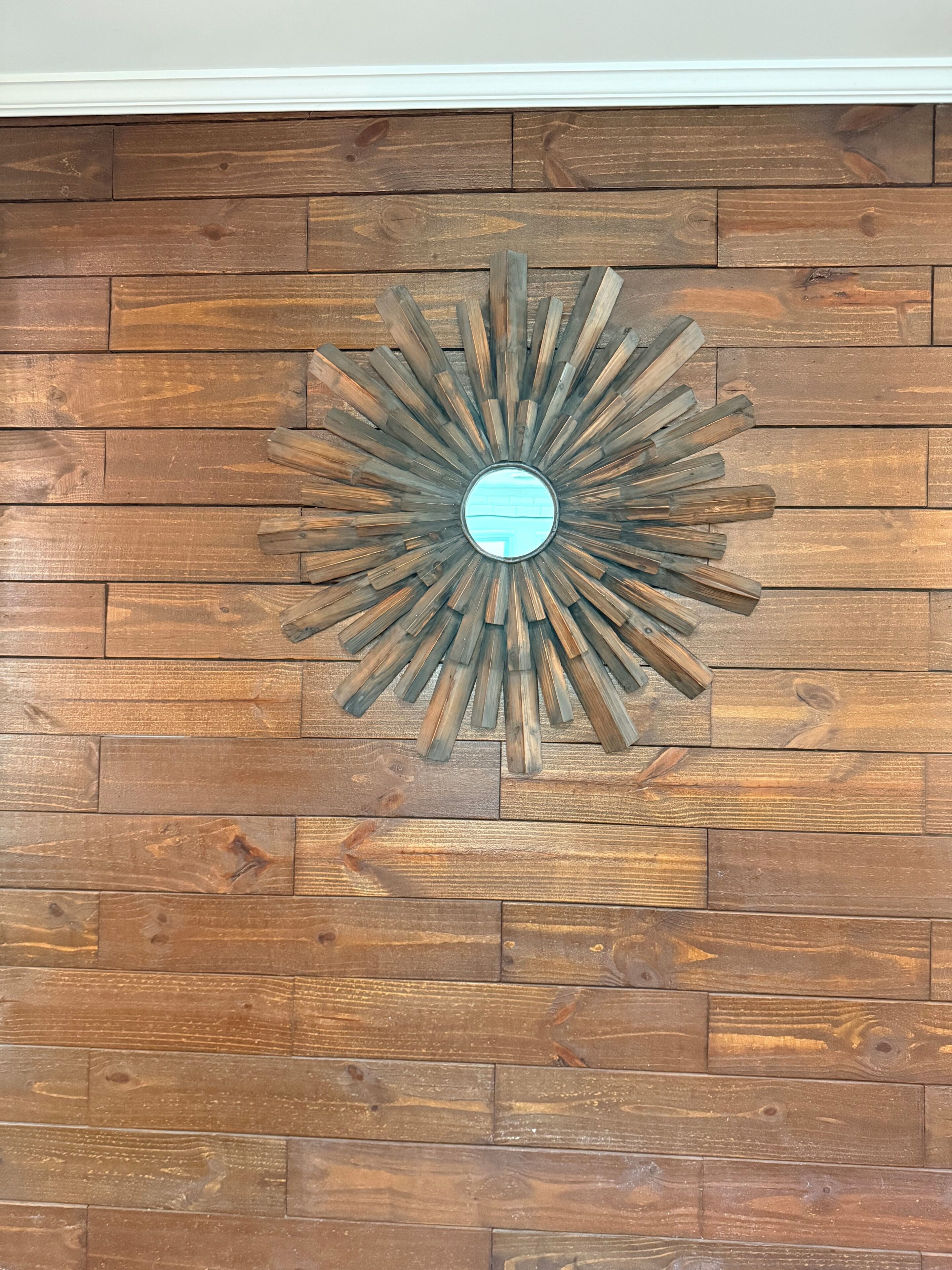 A wooden wall with a sunburst mirror decoration.