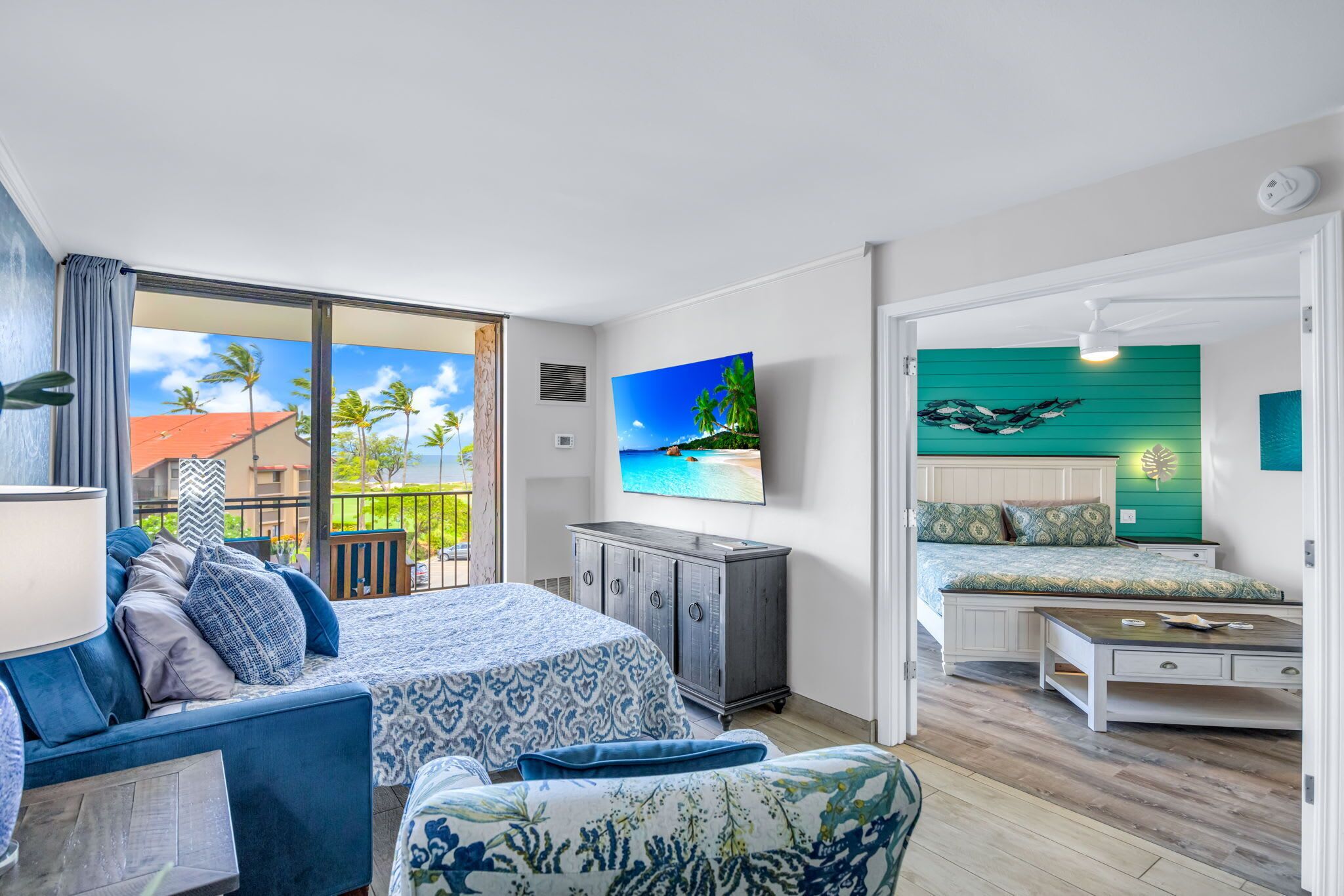 A bedroom with a bed, a desk, a TV, and a balcony with a view.