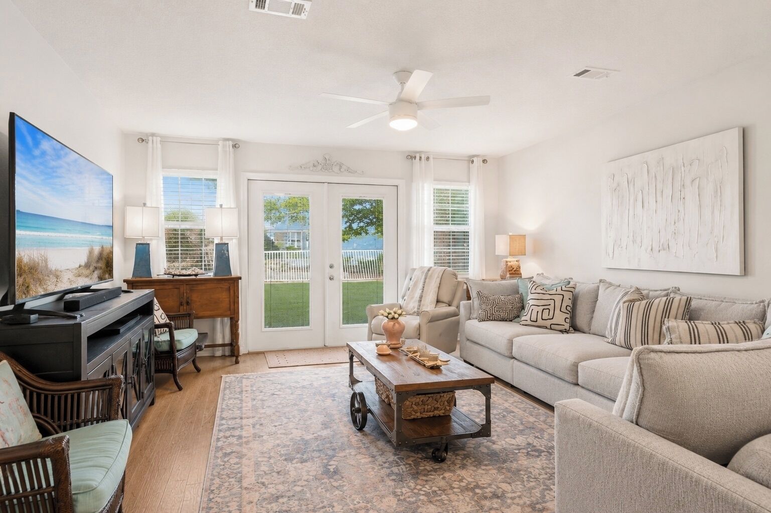 A living room with a television, sofa, coffee table, and a view of the outdoors through a glass door.
