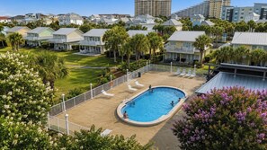 Área residencial com piscina, cercada por espreguiçadeiras e um deck com grade.