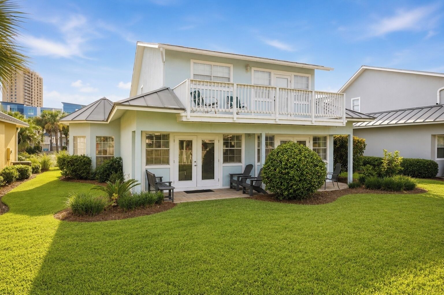 A two-story house with a balcony, a front porch with seating, and a well-maintained lawn.