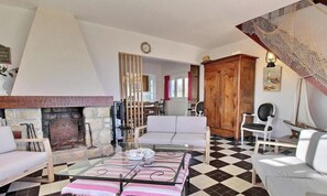 A living room with a fireplace, a sofa, a coffee table, and a dining area visible through an open doorway. - Stella du Parco - QUIBERON (QUIBERON)