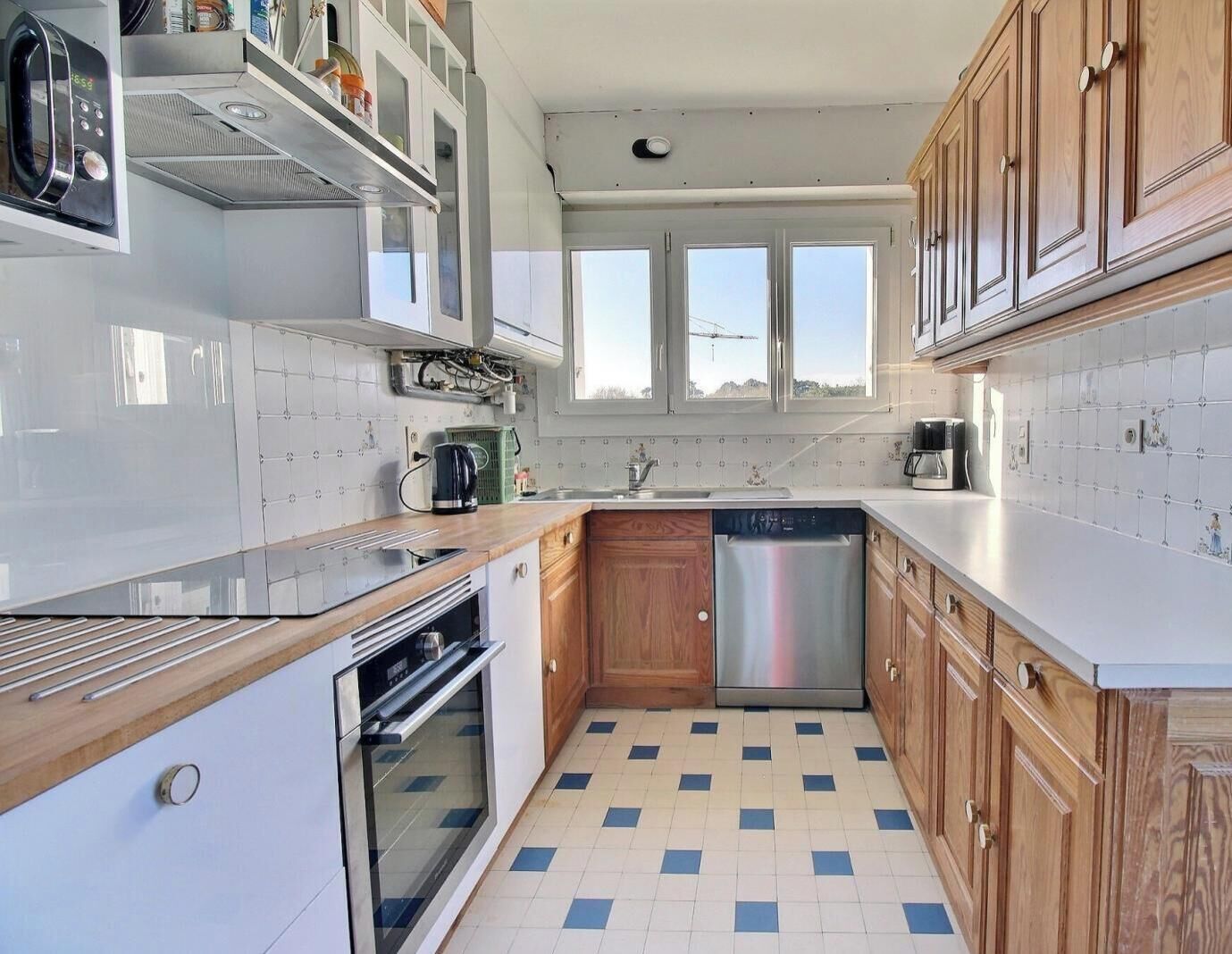 Cocina compacta con lavavajillas, horno y ventana sobre el lavabo.