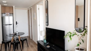 A compact living space with a kitchenette, a flat-screen TV, a dining area, and a potted plant. - Apartment Just Steps from Line 1, the Bus Terminal, and the Train Station (Estación Central)