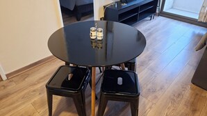 A round black table with two black stools, a small shelf with items, and a window with a view. - Apartment Just Steps from Line 1, the Bus Terminal, and the Train Station (Estación Central)