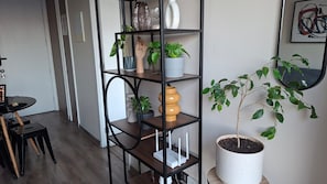 A room with a black metal shelving unit, a dining table with chairs, and a potted plant. - Fully equipped apartment, just steps from Line 1 (Estación Central)