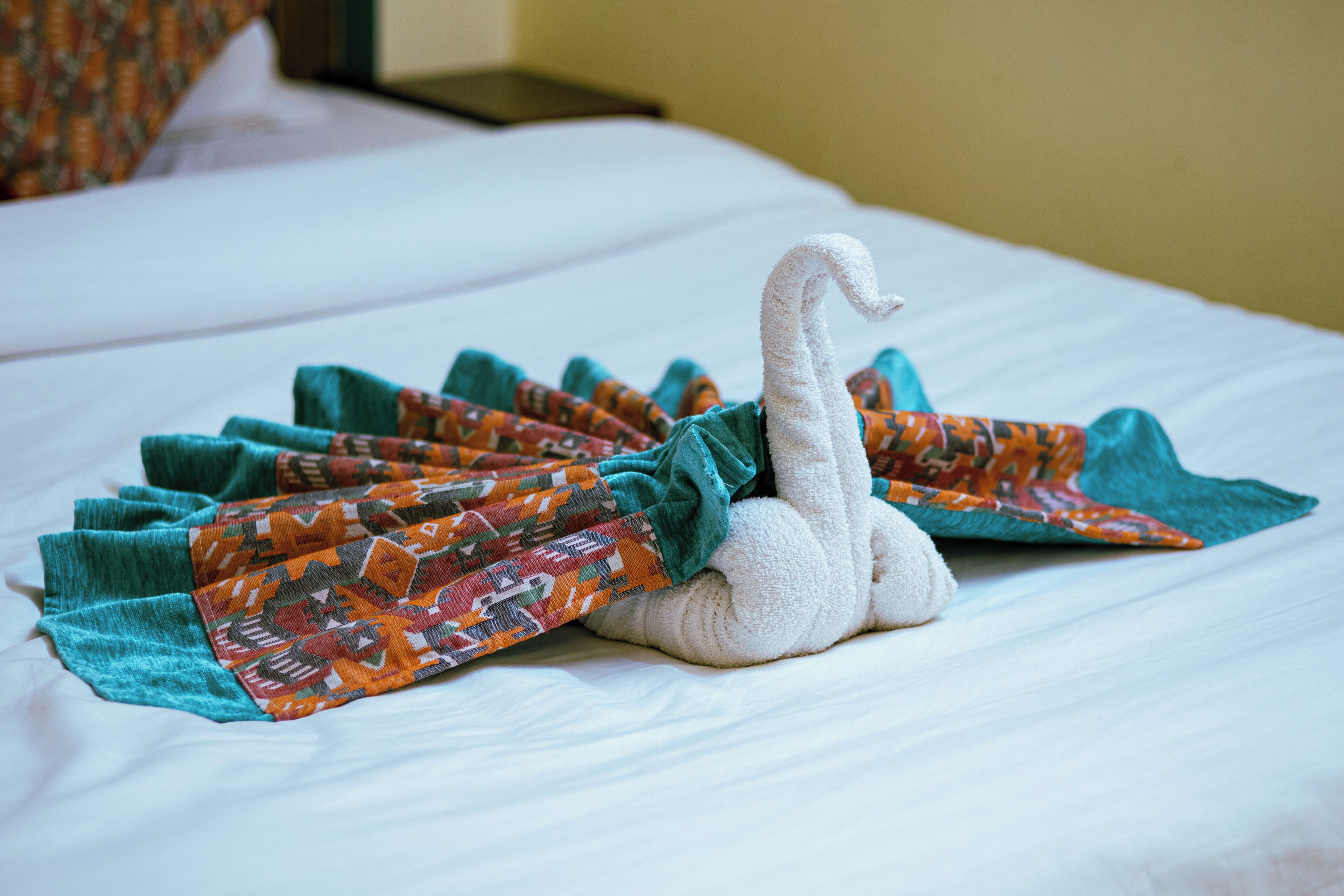 Ein Bett mit einem schwanenförmigen Handtuch und einer gemusterten Decke.