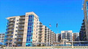 Un immeuble résidentiel à plusieurs étages doté de balcons, d’un mât sur lequel flotte le drapeau américain, et d’une enseigne indiquant « St. Augustine ».