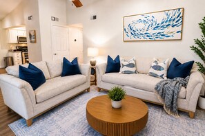 A living room with two sofas, a coffee table, and a painting on the wall. - Vita al Mare @ Seascape Resort (Miramar Beach)