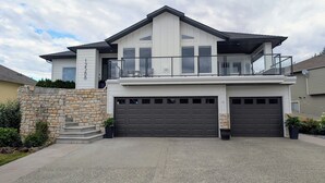 Ett modernt hus i två våningar med en fasad av sten, en balkong och två garageportar.