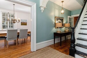 A dining area with a chandelier, a table with chairs, and a staircase.