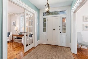 A room with a wooden floor, a white door, a chandelier, and a bench. - Kingsgate Lakehouse | Hot Tub & Private Dock (Delta)