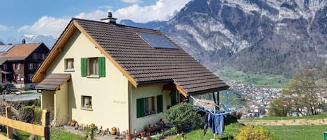 Une maison avec un toit en pente, des panneaux solaires et une vue sur les montagnes en arrière-plan.