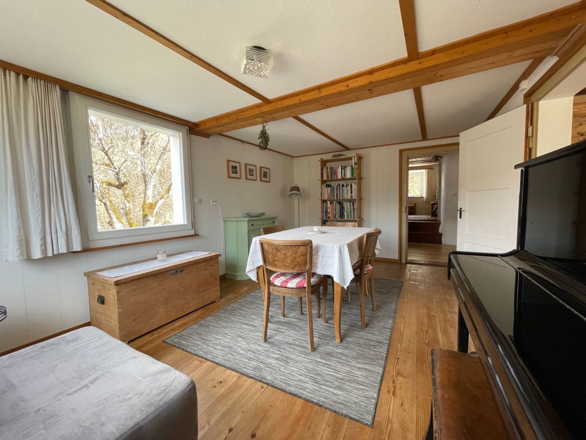 A cozy room with a dining table, chairs, a bookshelf, and a television.