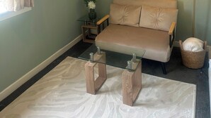 Habitació amb un sofà, una taula de centre de vidre, una làmpada i un vas decoratiu.