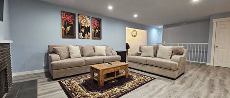 A living room with two sofas, a coffee table, and a patterned rug.