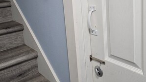 A white door with a silver handle and a keyhole, adjacent to a staircase with wooden steps and a white handrail. - Updated Modern Country Home - Pristine & Quiet - Near Seattle & Tacoma (Kent)