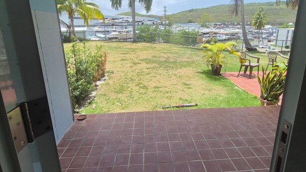 Vue depuis un patio abrité, doté d’un sol carrelé, d’une pelouse et de palmiers.