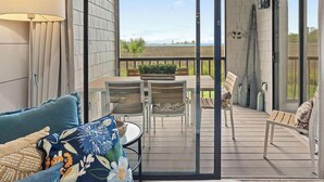 A covered outdoor seating area with a table and chairs, a sofa, and a view of the landscape. - BayviewPalms - Sandestin 2BR Bayview + Golf Cart (Miramar Beach)