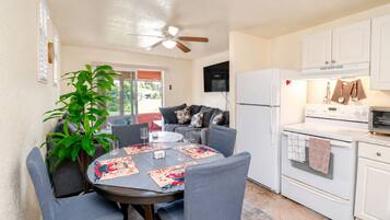 A compact kitchen with a dining area, a ceiling fan, and a large window.