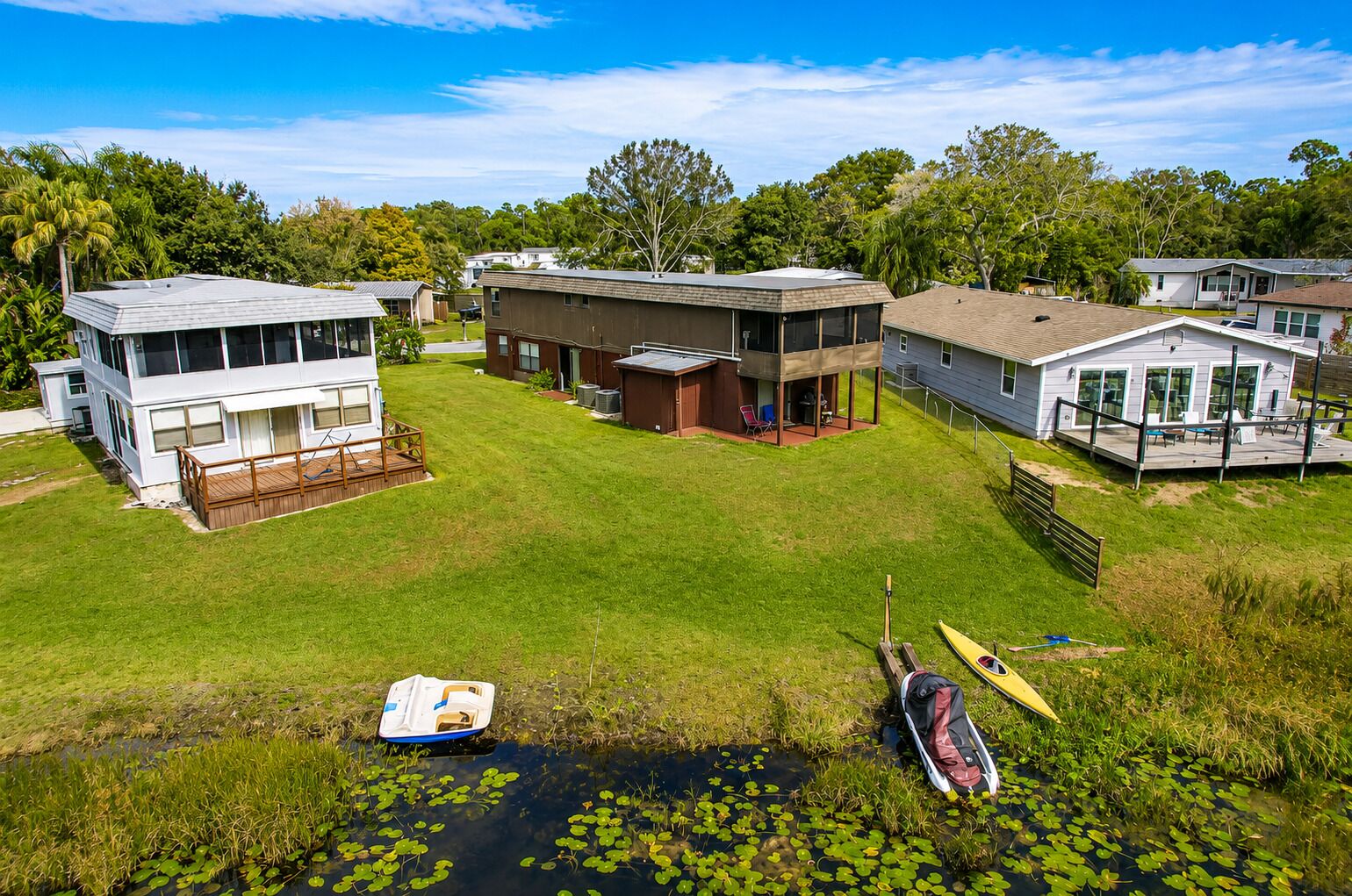 A residential area with houses, a grassy yard, and a small body of water with boats.
