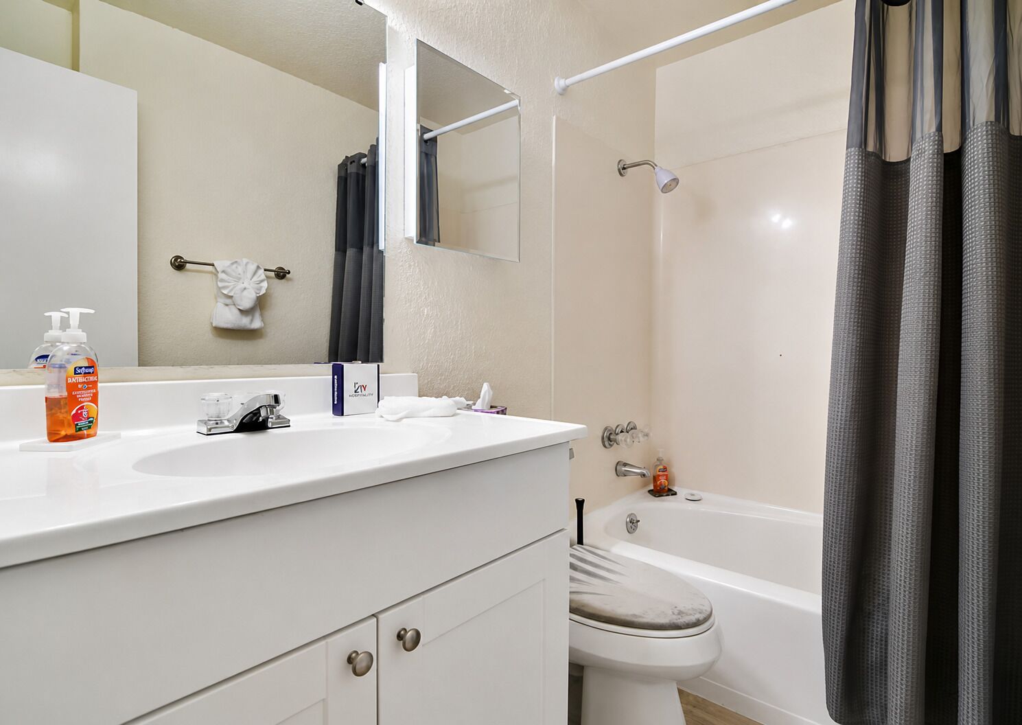 A bathroom with a white sink, a mirror, a towel rack, a toilet, and a shower curtain.