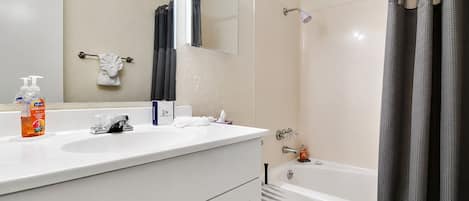 Un baño con lavamanos blanco, espejo, toallero, inodoro y cortina de ducha.
