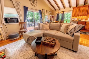 A cozy living room with a sectional sofa, a coffee table, and a view of the outdoors. - Charming 3-bedroom house in Arrowhead Lake (Pocono Lake)
