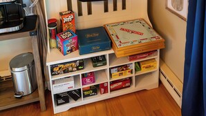 Een kamer met een welkomstbord, een bagagehouder en een plank met gezelschapsspellen.