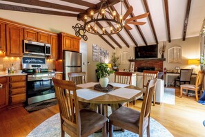 A kitchen with wooden cabinets, a built-in microwave, a stainless steel refrigerator, and a dining area with a wooden table and chairs. - Charming 3-bedroom house in Arrowhead Lake (Pocono Lake)